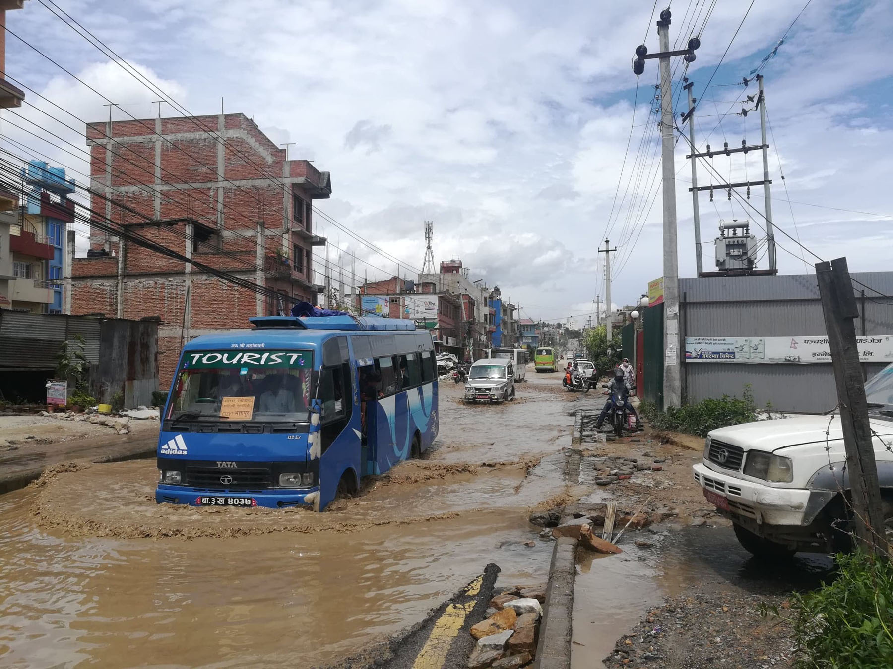 सडकमा खाल्डाखुल्डी भई पानी जमेर पोखरीजस्तै देखिएको दृश्य